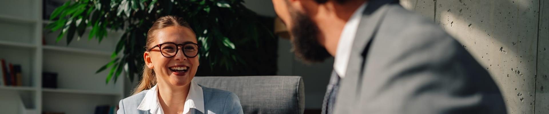 Frau und Mann in Businesskleidung bei einer Tasse Kaffee im Gespräch auf Sesseln sitzend